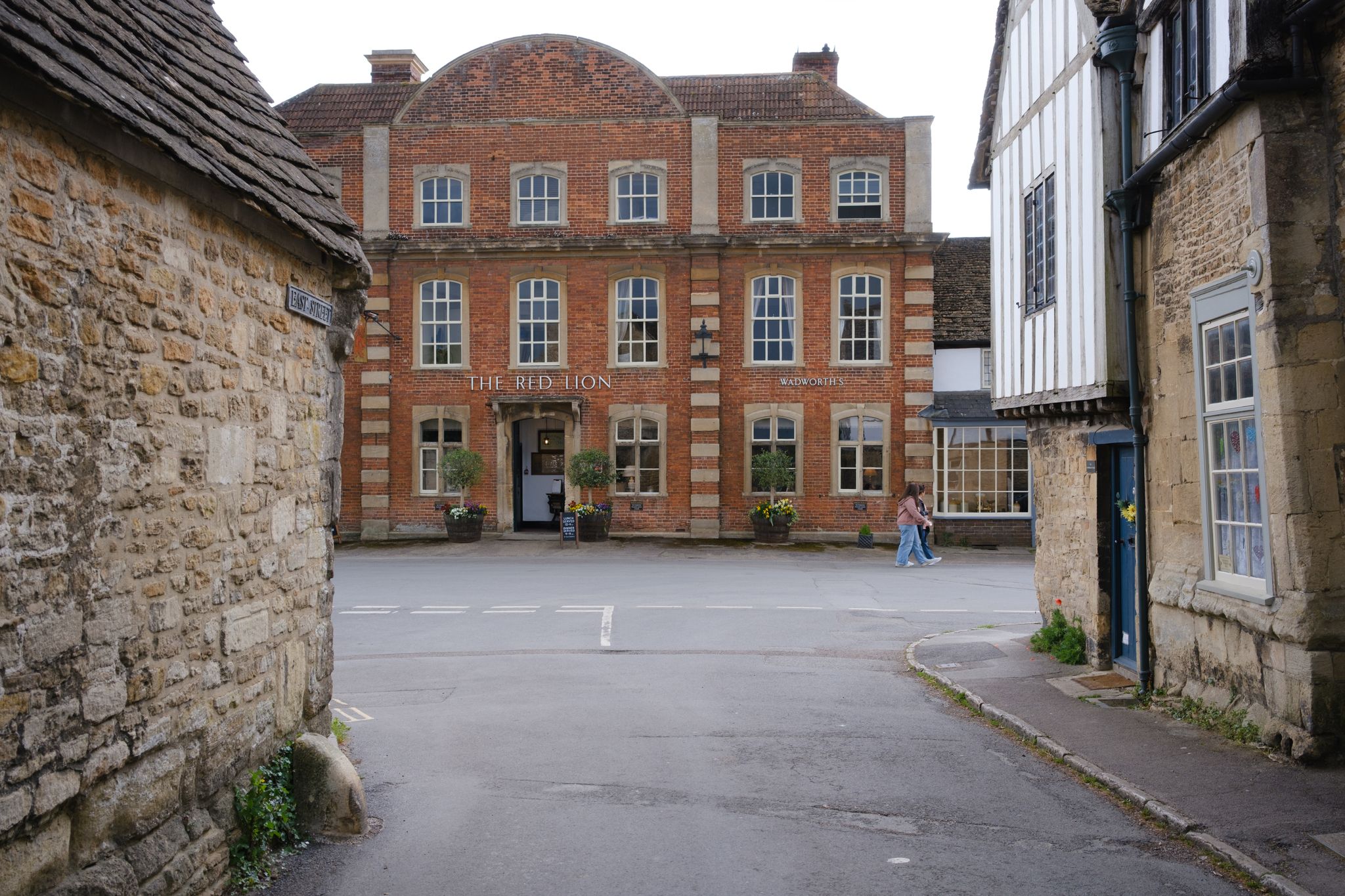 A picturesque view of the Red Lion pub in a quaint English village setting.